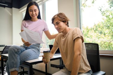 Asyalı kadın masasında, beyaz erkek arkadaşının yanında bir bardak kahve ile oturuyor.