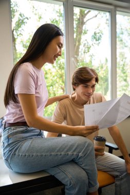 Asyalı kadın masasında, beyaz arkadaşının yanında bir bardak kahve ile oturuyor.
