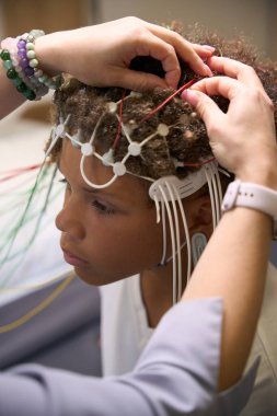 Hasta sakince oturuyor ve EEG cihazını ayarlıyor. Böylece elektrotların doğru beyin aktivitesi kaydı için yerleştirilmesi sağlanıyor.