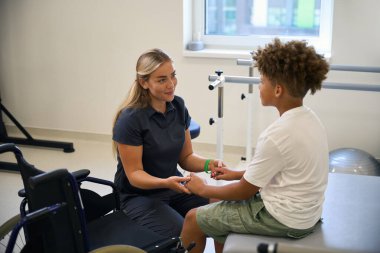 Genç hasta ve terapist terapi odasında otururken konuşuyorlar, ilerleme ve teknikleri tartışıyorlar.