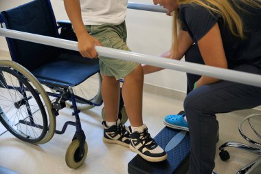 Yürüme egzersizi sırasında terapist elleri ve hastaların ayaklarının yakın plan çekimleri, adım kontrolü ve doğru konumlandırma vurgulanması