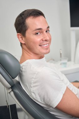 Kameraya yakından bakan adam dişçide otururken, stomatoloğu ziyaret ederek ilk aşamalarında sorunları tespit ediyor ve yüksek kalitede diş bakımı alıyor.