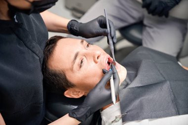 Yüksek nitelikli stomatolog, yeni hastaların diş ve diş etlerini inceleyerek tedavi planı ve fiyatı belirliyor ve sigorta formunu hazırlıyor.