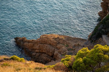 Costa Blanca 'daki sakin sahil sahnesinde engebeli kayalar ve yumuşak okyanus dalgaları var. Parlak gün ışığı huzurlu atmosferi güçlendirir, rahatlama ve yansıma için mükemmeldir..