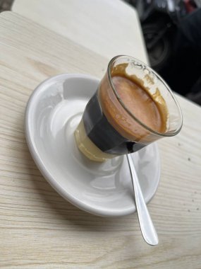 Güneşli bir sabahta karıştırılmaya ve tadını çıkarmaya hazır sütlü kahve. Acı kahve ve tatlandırılmış yoğunlaştırılmış süt. Bir dükkan ya da kafe içeceği menüsü. Bulanık arkaplan.