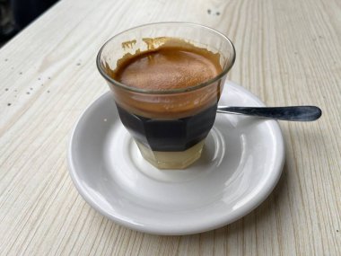 Güneşli bir sabahta karıştırılmaya ve tadını çıkarmaya hazır sütlü kahve. Acı kahve ve tatlandırılmış yoğunlaştırılmış süt. Bir dükkan ya da kafe içeceği menüsü. Bulanık arkaplan.