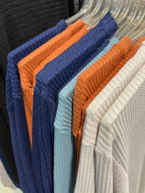 Askısı olan bir sürü tişört. Renkli tişörtler müşterilere sergilenmeye hazır. Yumuşak ve pürüzsüz pamuklu kumaşlar. Göstermelik askılar. Parlak renkli kumaş arkaplan kavramı