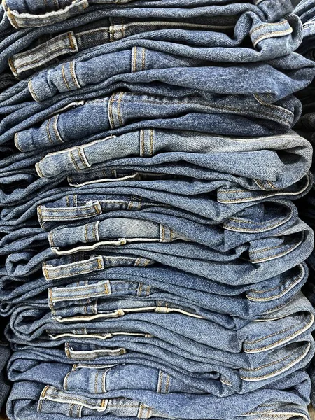 Pile of blue jeans ready for display and sale. jeans neatly arranged in the distro cupboard. Strong texture and seams on the pants. Neat trouser fold. mockup of a pile of pants for the design template