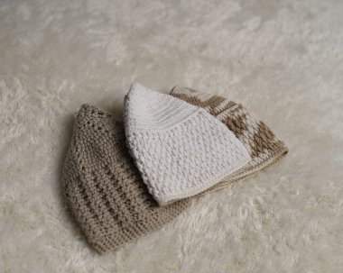 Songkok şapkaları koleksiyonu, Müslüman erkekler tarafından takılan dekoratif İslami başlıklar, farklı açılardan beyaz kürk halı arka planında izole edilmiş. Songkok elle bağlanmış Ramadhan Ramazan Bayramı 'ndan yapılır.