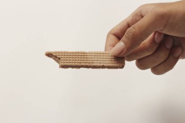 Beyaz ve ahşap arka planda çikolata aromalı kremalı gofretler. Çikolatalı Wafer. Çikolatalı Pipet. Farklı şekillerde lezzetli, çıtır çıtır gofretler. Uzun, kare, lezzetli ve çıtır çıtır..