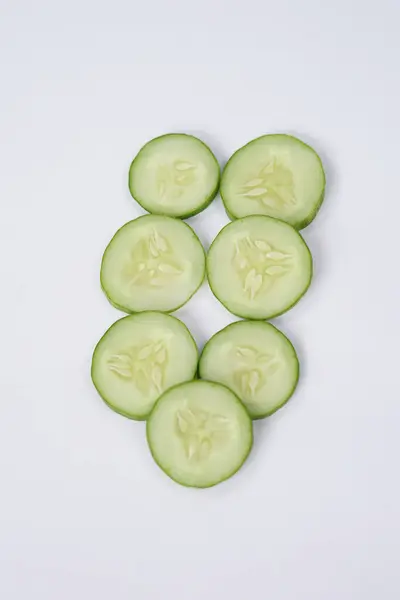 stock image Halves and slices of long cucumber isolated on white background. Green cucumber texture template arranged and harvested. Fresh cucumbers picked from the garden and sold on the shelves in the market.