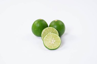 Limonlu meyve. Taze, keskin limonlu, parlak yeşil derili ve sulu bir içi var. Mutfak, sağlıklı ve turunçgiller için ideal. Beyaz arka planda dilimlenmiş olgun kireç meyveleri..