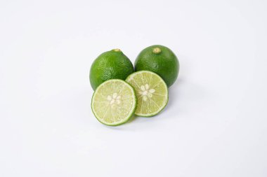 Limonlu meyve. Taze, keskin limonlu, parlak yeşil derili ve sulu bir içi var. Mutfak, sağlıklı ve turunçgiller için ideal. Beyaz arka planda dilimlenmiş olgun kireç meyveleri..