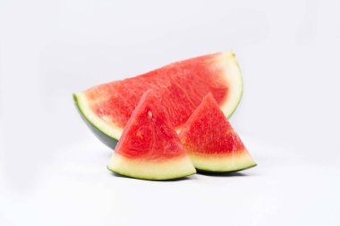 Tam karpuz ve tohum dilimleri beyaz arka planda önden ve üstten görülüyor. Karpuz dilimleri kırmızı, köhne ve suludur..