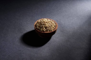 Koyu arka planda izole edilmiş ahşap kasede kişniş tohumu, baharat konsepti