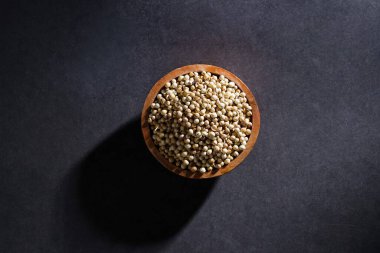 Koyu arka planda izole edilmiş ahşap kasede kişniş tohumu, baharat konsepti