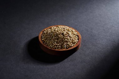 Koyu arka planda izole edilmiş ahşap kasede kişniş tohumu, baharat konsepti