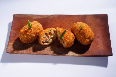 Lezzetli Endonezya atıştırmalığı Risol ya da biftek mayonezi ile doldurulmuş risoleler ve ahşap bir tabakta kızarmış ekmek kırıntısı dokusu, beyaz bir arka planda izole edilmiş.