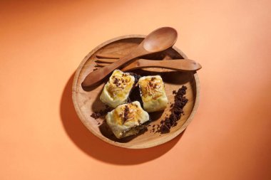 Banana bolen is made from banana and pastry skin and has chocolate and cheese filling. Served in wooden plate. Selective focus image. clipart