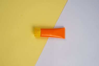 Beyaz ve sarı arkaplanda izole edilmiş güneş kremi tüpü. Vücut bakımı güzellik tedavi konsepti