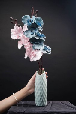 Siyah arka plandaki vazoda pembe ve gri bahar çiçekleri. Yüksek çözünürlüklü. Seçici odak.