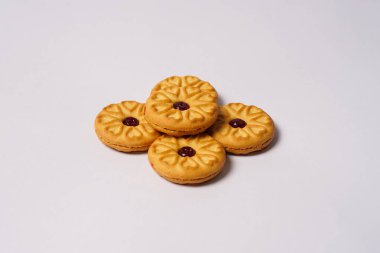 Beyaz arka planda çilekli bisküviler, yüzeylerinde dairesel kalp motifi ile süslenmiş. Yüksek çözünürlüklü fotoğraf.