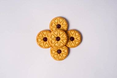 Beyaz arka planda çilekli bisküviler, yüzeylerinde dairesel kalp motifi ile süslenmiş. Yüksek çözünürlüklü fotoğraf.