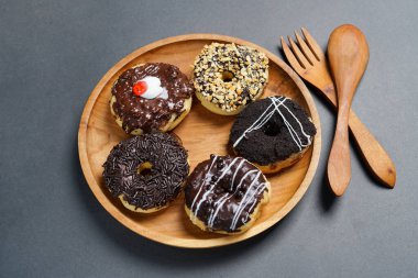 Ahşap tabakta farklı malzemelerle servis edilen çörekler, siyah arka planda üst manzara. Yüksek çözünürlüklü fotoğraf.