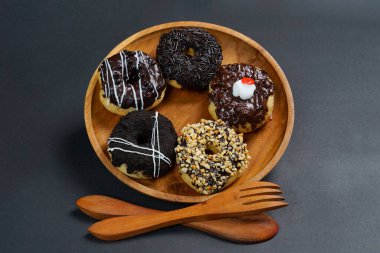 Ahşap tabakta farklı malzemelerle servis edilen çörekler, siyah arka planda üst manzara. Yüksek çözünürlüklü fotoğraf.