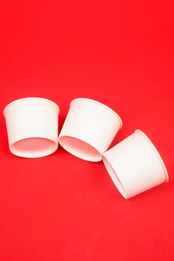 Tek kullanımlık kağıt kasenin yan görüntüsü, kırmızı arka planda izole edilmiş. Yüksek çözünürlüklü fotoğraf.