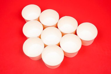 Tek kullanımlık kağıt kaseler, kırmızı arka planda izole edilmiş. Yüksek çözünürlüklü fotoğraf.