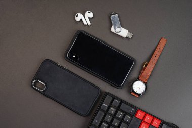 Kulaklığı ve siyah arka planda izole edilmiş lüks saati olan akıllı telefon manzaralı. Yüksek çözünürlüklü fotoğraf.