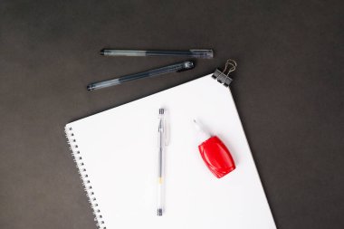 Siyah arkaplanda kalem ve düzeltme kalemli okul defteri, masada spiral not defteri