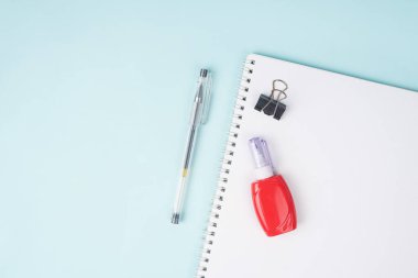 Mavi arka planda kalem ve düzeltme kalemli okul defteri, masada spiral defter