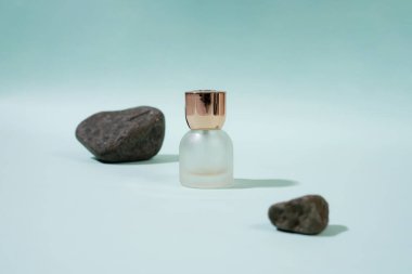 Mavi Arkaplanda Minimalist Kozmetik Şişesinin Yaşamı ve Taşlar