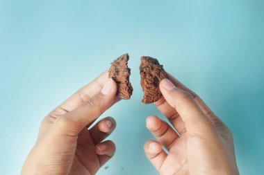 Mavi arka planda bir kurabiye elle kırılıyor..