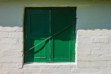 Eski pencere yeşil panjurlarla kapatılmış.