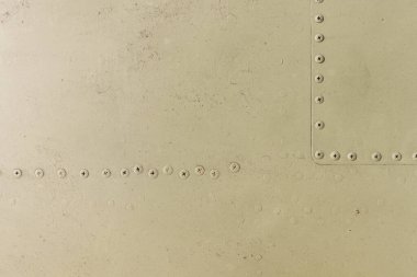 Eski bir uçağın gövdesinin detayları. Askeri bir uçağın üzerinde boya ve perçin ile kamuflaj yüzeyi.