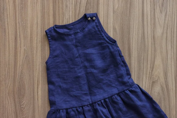 Children's linen clothes. Blue children's dresson a wooden background. Top view.