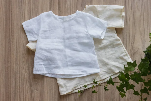 Children\'s linen clothes. White linen shirt on a wooden background. Top view