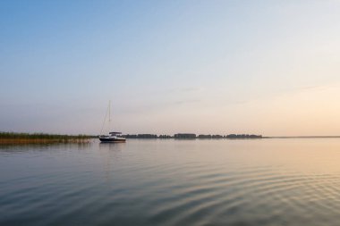 Günbatımında yelkenli teknesi aydınlanır. Gölde gün batımı.