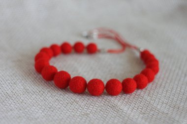 Hafif arka planda kırmızı keçeli yün kolye.