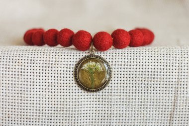 Hafif arka planda kolyesi olan bir kolye. Keçeli Yün Kolye