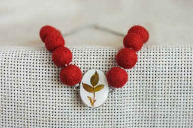 Hafif arka planda kolyesi olan bir kolye. Keçeli Yün Kolye