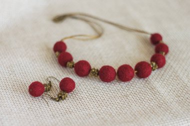 Kolyesi ve hafif arka planda küpeleri olan bir kolye. Keçeli yün kolye