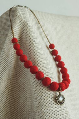 Hafif arka planda kolyesi olan bir kolye. Keçeli Yün Kolye