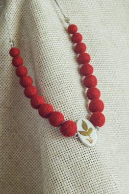 Hafif arka planda kolyesi olan bir kolye. Keçeli Yün Kolye