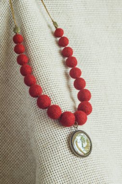 Hafif arka planda kolyesi olan bir kolye. Keçeli Yün Kolye