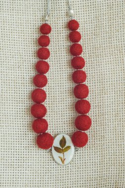 Hafif arka planda kolyesi olan bir kolye. Keçeli Yün Kolye