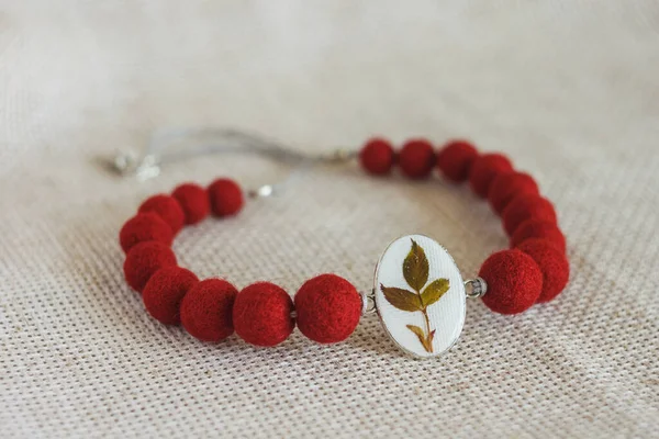 Hafif arka planda kolyesi olan bir kolye. Keçeli Yün Kolye